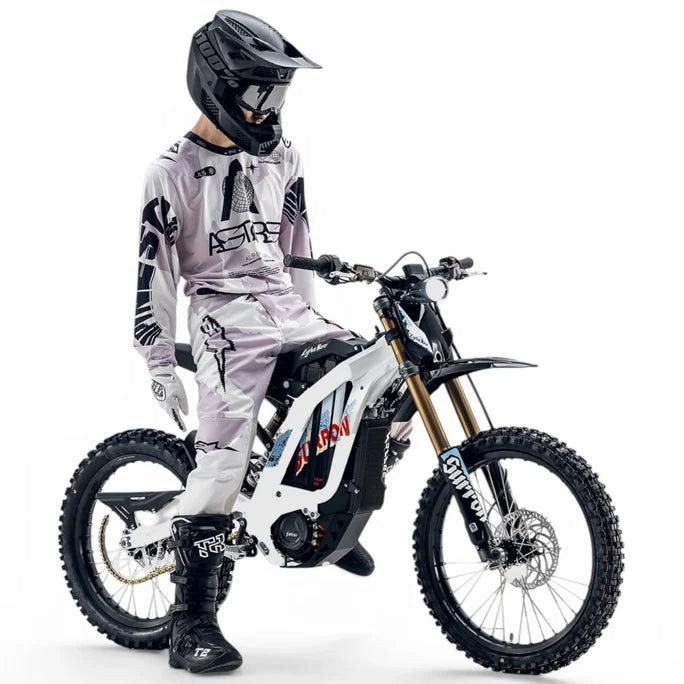 Surron Light Bee X 2026 electric dirt bike with black frame and knobby tires, displayed outdoors on a trail.